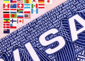 Close-up of a large blue 'USA' graphic with a row of small international flags above it on a pink background.