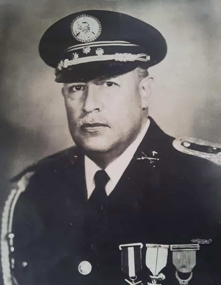 Retrato oficial del coronel Enrique Peralta Azurdia en 1964, Gobernó hasta 1966. – SoyMigrante.com REVISTA – SoyMigrante.com REVISTA Black-and-white portrait of a senior military officer in dress uniform, wearing a peaked cap with insignia and medals on the chest.