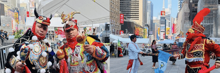 Two performers in ornate festival costumes pose for a photo at a busy city street festival, with tents, vendors, and tall buildings in the background.