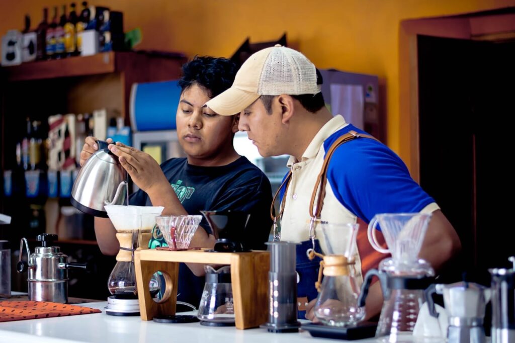 Ángel, enseñando el arte de la preparación de café a su hijo mayor en Momostipán, en el corazón del casco urbano de Momostenango