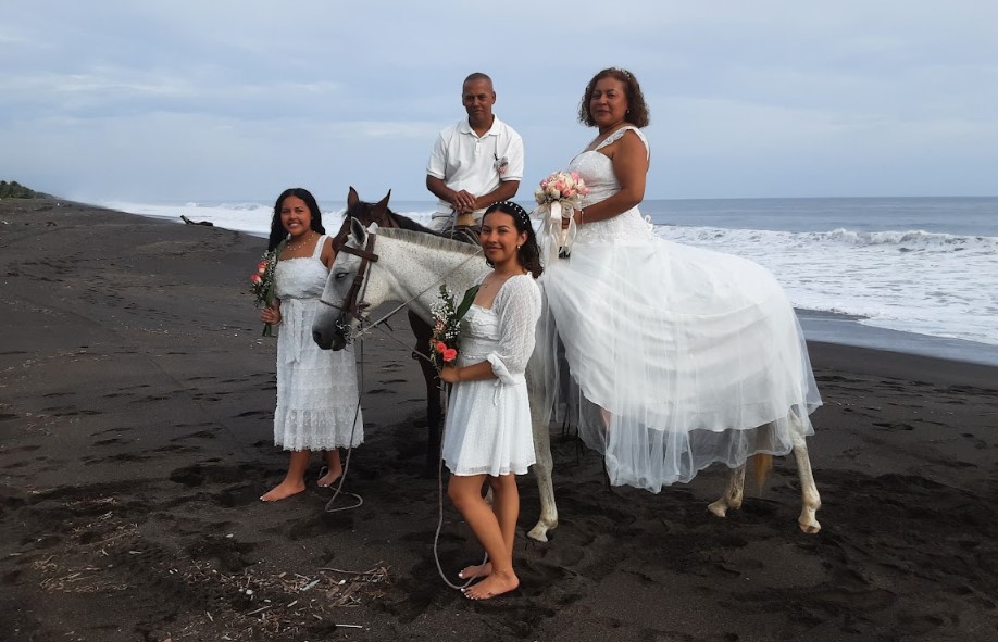 Los migrantes guatemaltecos Daniel y Yezenia, junto a sus hijas Allison y Kimberly Letrán Martínez, posan con alegría poco antes de la ceremonia en la cual conmemoraron 25 años de matrimonio en la playa de Monterrico, Taxisco, Santa Rosa, Guatemala.