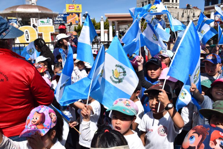 Niños, niñas y familias de varios establecimientos acompañan la caravana, banderas en azul y blanco abundan en las festividades