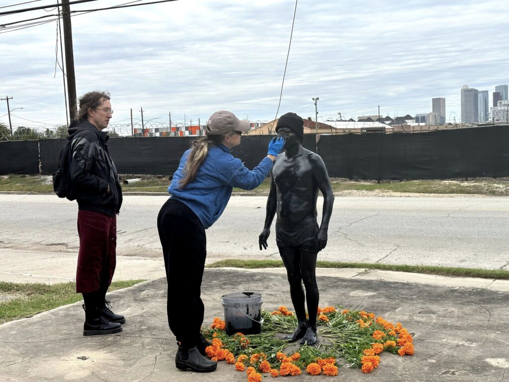 Estudiantes y profesores de la Universidad de Houston ayudan al artita a completar la cobertura negra hasta el rostro