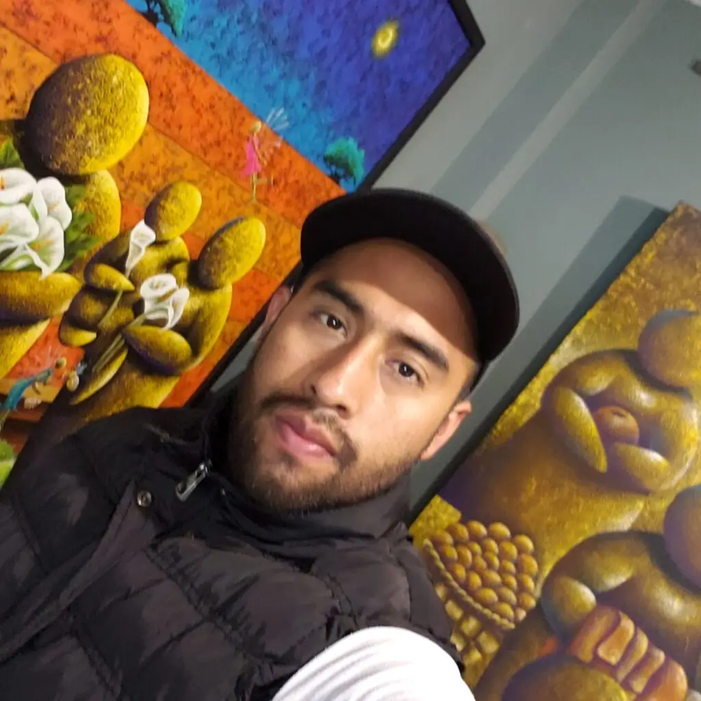 Eddy Vásquez posa frente a la colección de pinturas que exhibe en Francia. – SoyMigrante.com – SoyMigrante.com