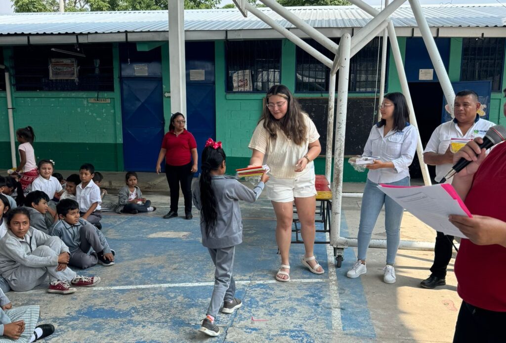 Trisha Martínez, voluntaria de Quetzi, entrega algunos de los útiles escolares a los niños. Su alegría fue conmovedora y nos anima a seguir adelante con el esfuerzo de donar recursos educativos. – SoyMigrante.com – SoyMigrante.com