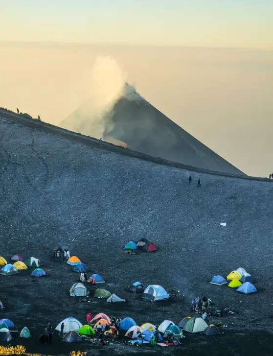 Exploradores acampan en el volcán de Acatenango, que hoy está inactivo. Al fondo se ve el volcán de Fuego, que lanza constantes fumarolas y explosiones. Fotografía Abel Juárez. – SoyMigrante.com – SoyMigrante.com