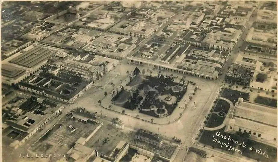 Vista aérea del centro de la ciudad de Guatemala: Enmedio puede verse el Parque Central; a la izquierda, la Catedral Metropolitana no tenía torres de campanario porque fueron destruidas por los terremotos de 1917-18; arriba del Parque está el Portal del Comercio, que fue remodelado en 1924. Justo encima del Portal puede verse el Pasaje Aycinena, que es considerado como el primer centro comercial; abajo está el predio donde actualmente se encuentra el Palacio Nacional, pero este fue construido hasta 1943. En 1924, todavía estaba vacío y únicamente tenía el Palacio Chino, una estructura obsequiada por la colonia china en el país: a la derecha, del lado opuesto a la Catedral se puede ver aún el llamado Palacio de Cartón, construido para celebrar el centenario de independencia en 1921, pero que se incendió aquel 1924. La ciudad de Guatemala tenía en 1924. Detrás de la Catedral se observa el antiguo Mercado Central, construido en 1868 y que fue destruido por terremotos. La capital tenía poco más de 100 mil habitantes hace 100 años. – SoyMigrante.com – SoyMigrante.com