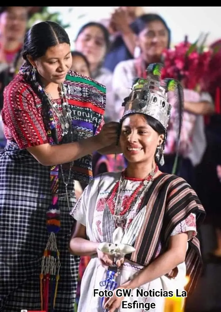 Momento en que la Rabín Ajau saliente, Madelyn Miranda Toyom, coloca la corona de plata con plumas de quetzal a Arly Paola Cholotío, de San Juan La Laguna como nueva Rabin Ajau, Hija del Rey 2024-25 (Foto Cortesía Angel Martín Tax, noticias La Esfinge) – SoyMigrante.com – SoyMigrante.com